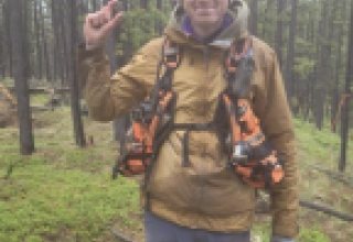 a man holding a point in a forest