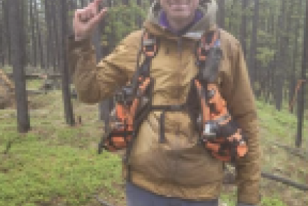 a man holding a point in a forest